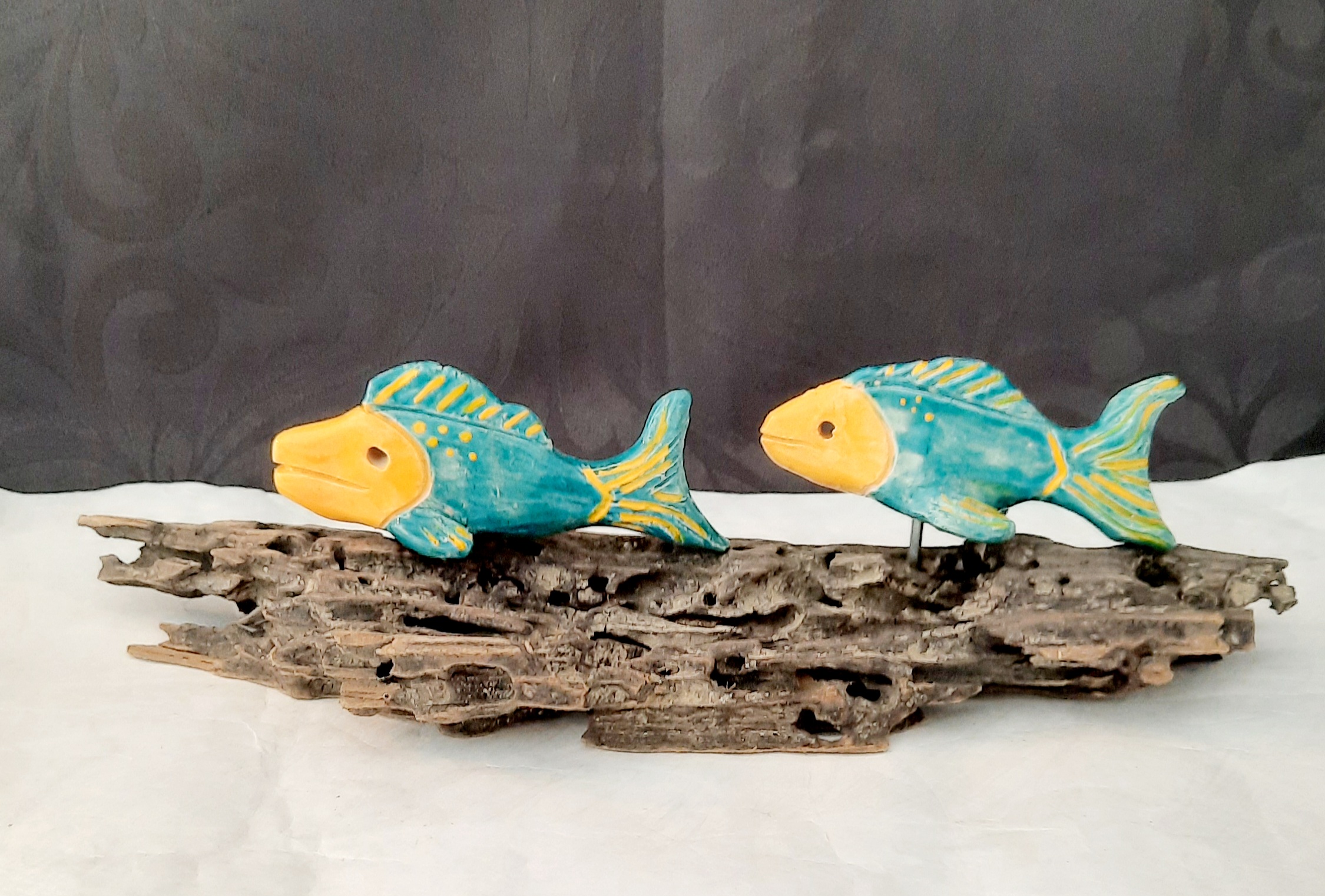 Deux poissons en céramique bleu et orange sur bois flotté