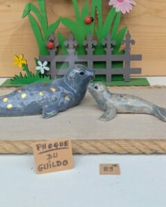 Phoques décoratifs en céramique posés sur bois flotté dans un décor naturel